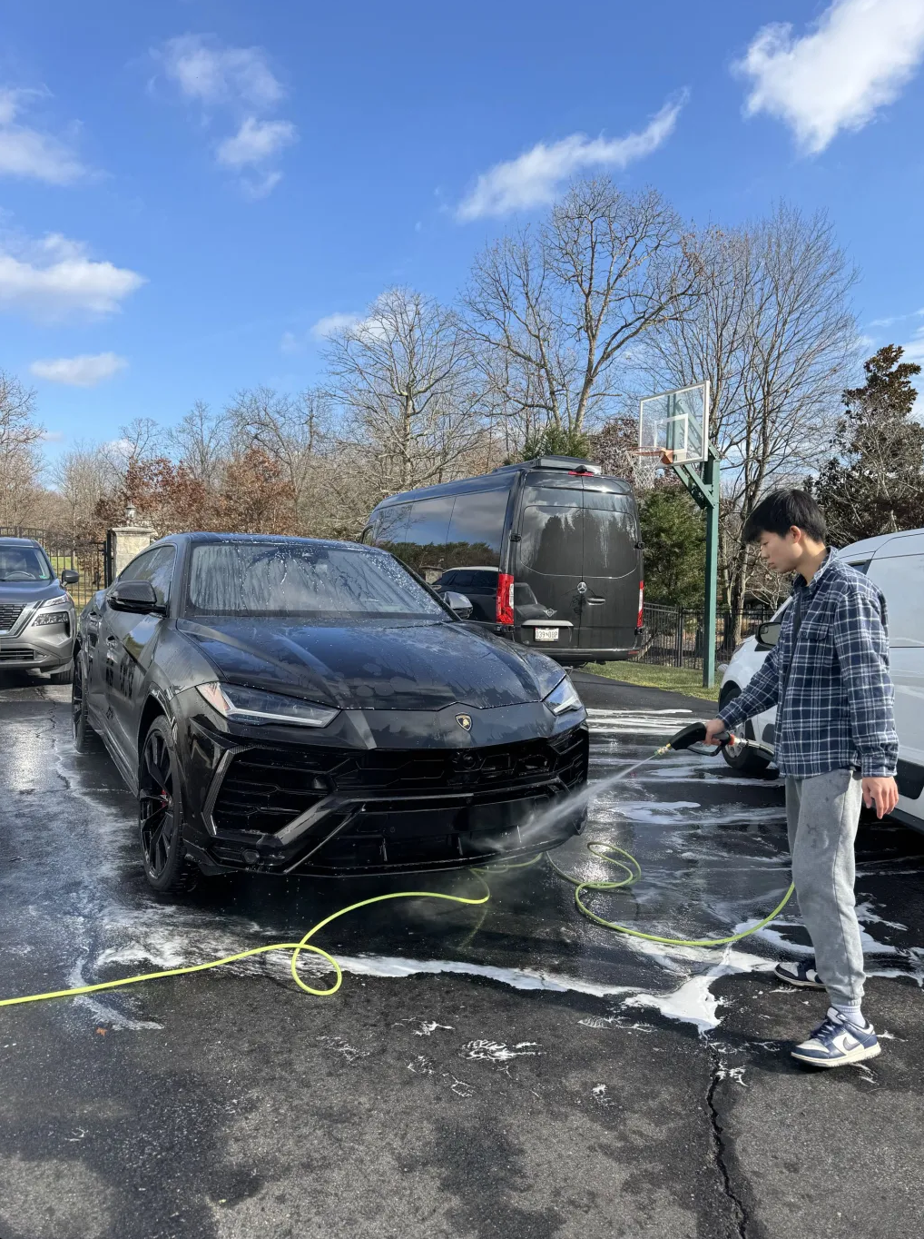 Polaris detailer hand-polishing a luxury SUV in a sunlit driveway